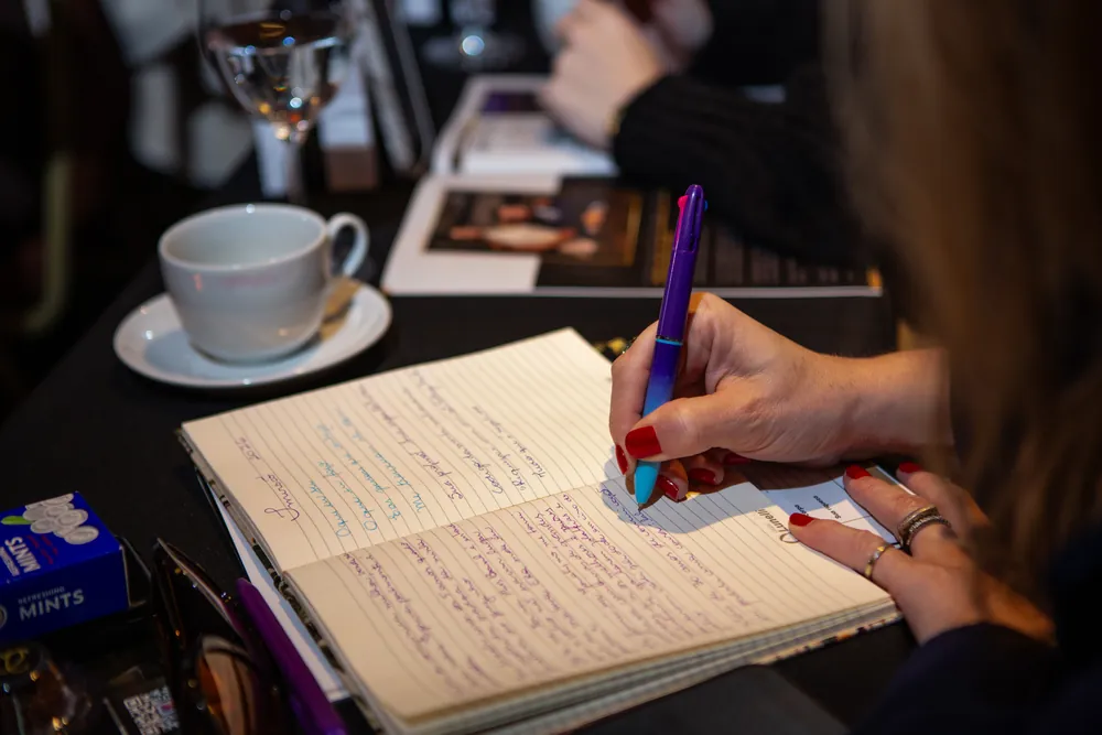 Participante fazendo anotações em caderno durante evento
